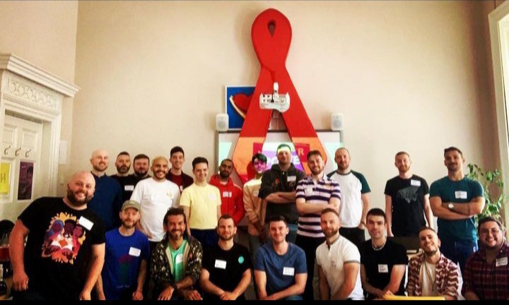 MPOWER volunteers at a training event standing in two lines with a big red ribbon